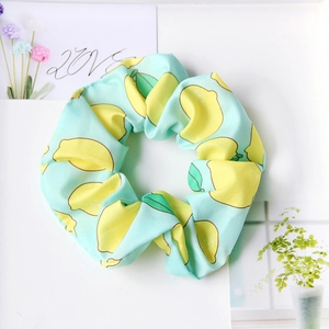 Detail of light green hair scrunchie featuring cute yellow lemon patterns on fabric