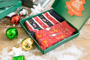 Detailed view of red and black Christmas socks with reindeer patterns in festive gift box