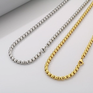 Detail of silver and gold stainless steel box chains with lobster clasps on white surface