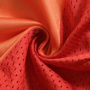Gros plan du tissu en maille respirante aux tons orange vif et rouge sportifs