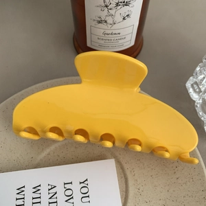 Close-up of a large yellow acetate hair claw clip on a decorative ceramic plate