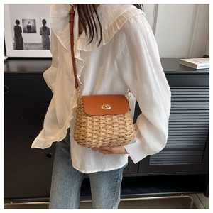 Detail of hand-woven straw crossbody bag with brown leather flap and gold twist lock