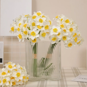 Artificial white narcissus flowers in a striped glass vase for home decoration