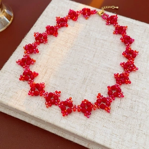 Detail of red and orange beaded floral necklace on a beige fabric notebook