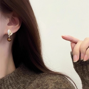 Boucles d'oreilles boules œil de tigre plaquées or portées par un mannequin chic
