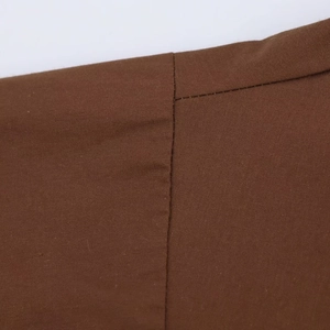 Detailed view of dark brown poplin fabric texture and professional stitching on the shirt