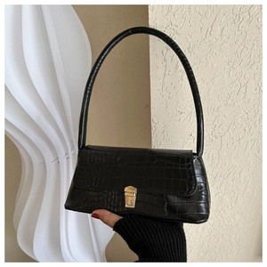 Detail view of black crocodile pattern baguette bag with a golden rectangular lock