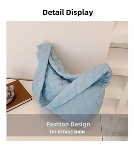 Close-up of light blue quilted nylon shoulder bag with soft pleated texture and zipper