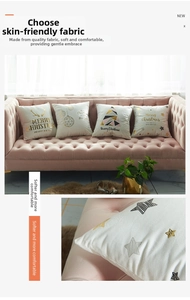 Detail of white Christmas cushion covers with gold deer and tree prints on a velvet sofa