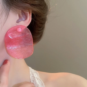 Close-up of translucent pink resin chip earring with textured finish on model