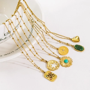 Colliers vintage en acier doré avec pendentifs étoile et pierre naturelle sur tasse blanche