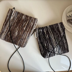 Detail of vintage striped woven crossbody bags in coffee and black tones with side labels