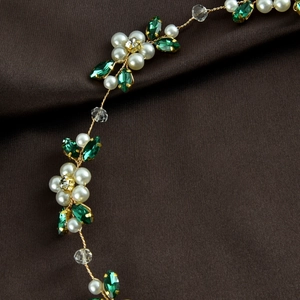 Detail of bridal hair vine with white pearls and green crystal leaves on gold wire