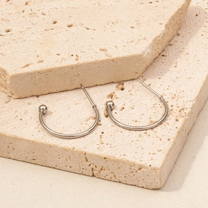 Macro detail of silver 304 stainless steel C-shaped earrings with ball ends on stone