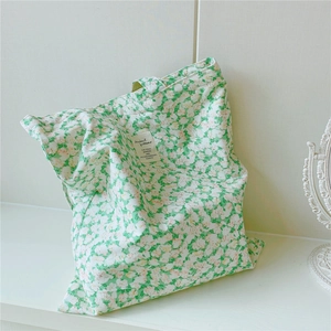 Close-up of green and white floral cotton tote bag with a minimalist woven label