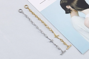Detail of gold and silver heartbeat pulse bracelets with toggle clasps on a textured base