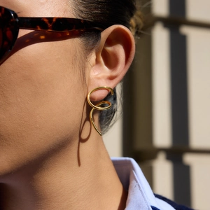 Minimalist gold spiral hoop earrings with linear wrap design on a female model