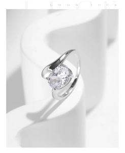 Macro shot of silver ring featuring a large oval clear gemstone on a geometric white stand