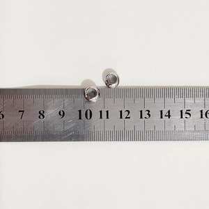 Macro shot of 10mm polished stainless steel DIY bracelet connector beads on a metric scale