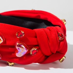 Primer plano de diadema roja de tela con lentejuelas de corazón y brillantes dorados