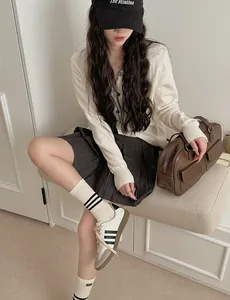 Detail of trendy striped mid-calf socks styled with a pleated skirt and casual sneakers