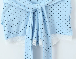 Detail of light blue polka dot romper showing white lace trim and waist tie bow