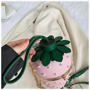 Détail du sac seau fraise rose avec perles blanches et bandoulière chaîne dorée