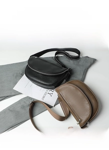 Detail of soft leather crescent bags in black and brown with striped canvas shoulder straps
