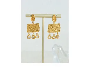 Detailed close-up of vintage gold hammered metal earrings with three sparkling zircons