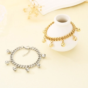 Detailed shot of gold and silver chain bracelets with bell charms on a white vase