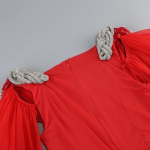 Détail de robe de soirée rouge montrant le nœud perlé et la manche en mousseline