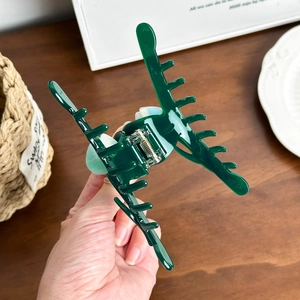 Large dark green acetate tulip claw clip held in hand for size and hair accessory detail