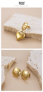 Detail showing gold heart earrings and square studs with cross-hatch texture on rock