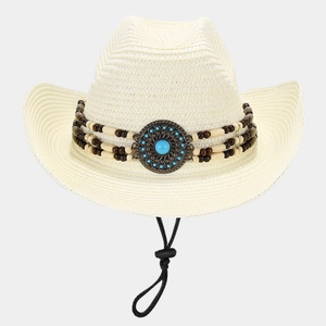 Close-up of straw cowboy hat with turquoise metal emblem and wooden bead trim