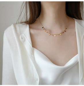 Detail of elegant gold titanium necklace with teardrop charms on a model neck