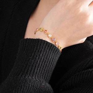 Close-up of elegant 18K gold bracelet featuring colorful round-cut zircon stones on a wrist
