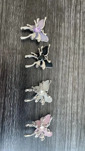 Detail of four butterfly-shaped metal brooches with colored resin and center gems