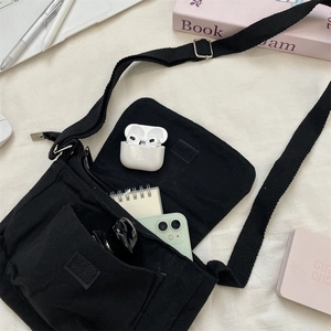 Internal storage detail of black canvas messenger bag showing phone and accessories