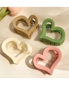 Macro view of four matte heart-shaped hair clips in cream, green, apricot, and pink shades