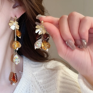 Détail de boucles d'oreilles fleuries avec perles d'ambre et longues pampilles sur modèle