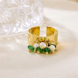Detailed close-up of gold wide-band open ring with white pearls and green gemstones