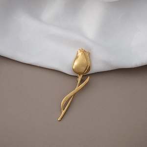 Elegant gold tulip flower brooch with metallic luster on white fabric background
