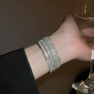 Vista dettagliata di lussuosi bracciali multistrato in argento con strass scintillanti al polso