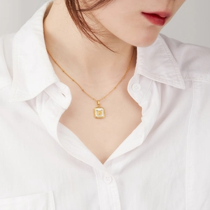 Collier doré vintage français avec pendentif carré en nacre et motif papillon sur une chemise