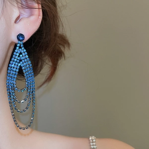 Gros plan de boucles d'oreilles à pompons en strass bleu foncé portées par un mannequin