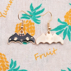 Détail des boucles d'oreilles chauve-souris d'Halloween avec motifs émaillés dorés