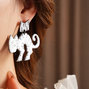 Close-up of minimalist silver cat earrings with crown detail on a model's ear