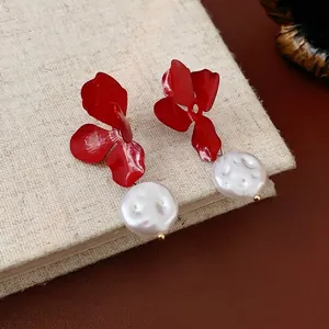 Red flower earrings with irregular baroque pearl drops on a vintage textured book