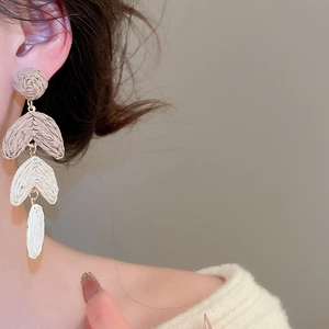 Close-up of bohemian woven raffia tassel earrings with gold-toned metal connectors
