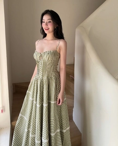 Detailed view of green plaid midi dress with delicate white lace trim on a staircase
